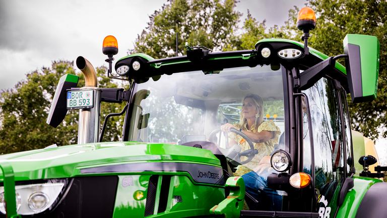 Die niederlämdische Königin Máxima sitzt in einem grünen Traktor. 