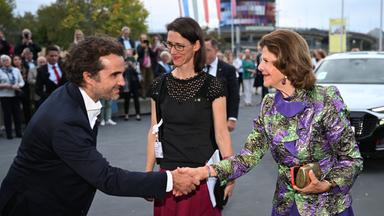 Das Bild zeigt Schauspieler Oliver Wnuk, der Königin Silvia von Schweden begrüßt.