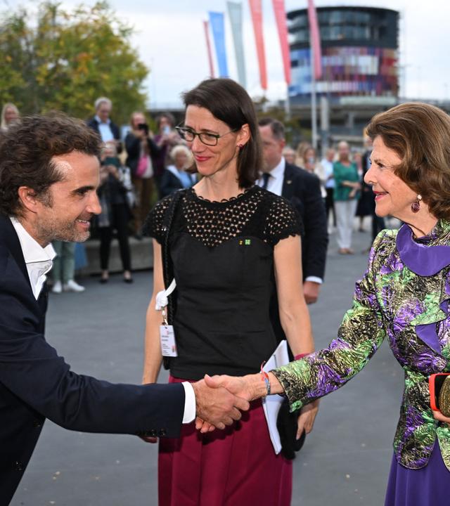 Das Bild zeigt Schauspieler Oliver Wnuk, der Königin Silvia von Schweden begrüßt.