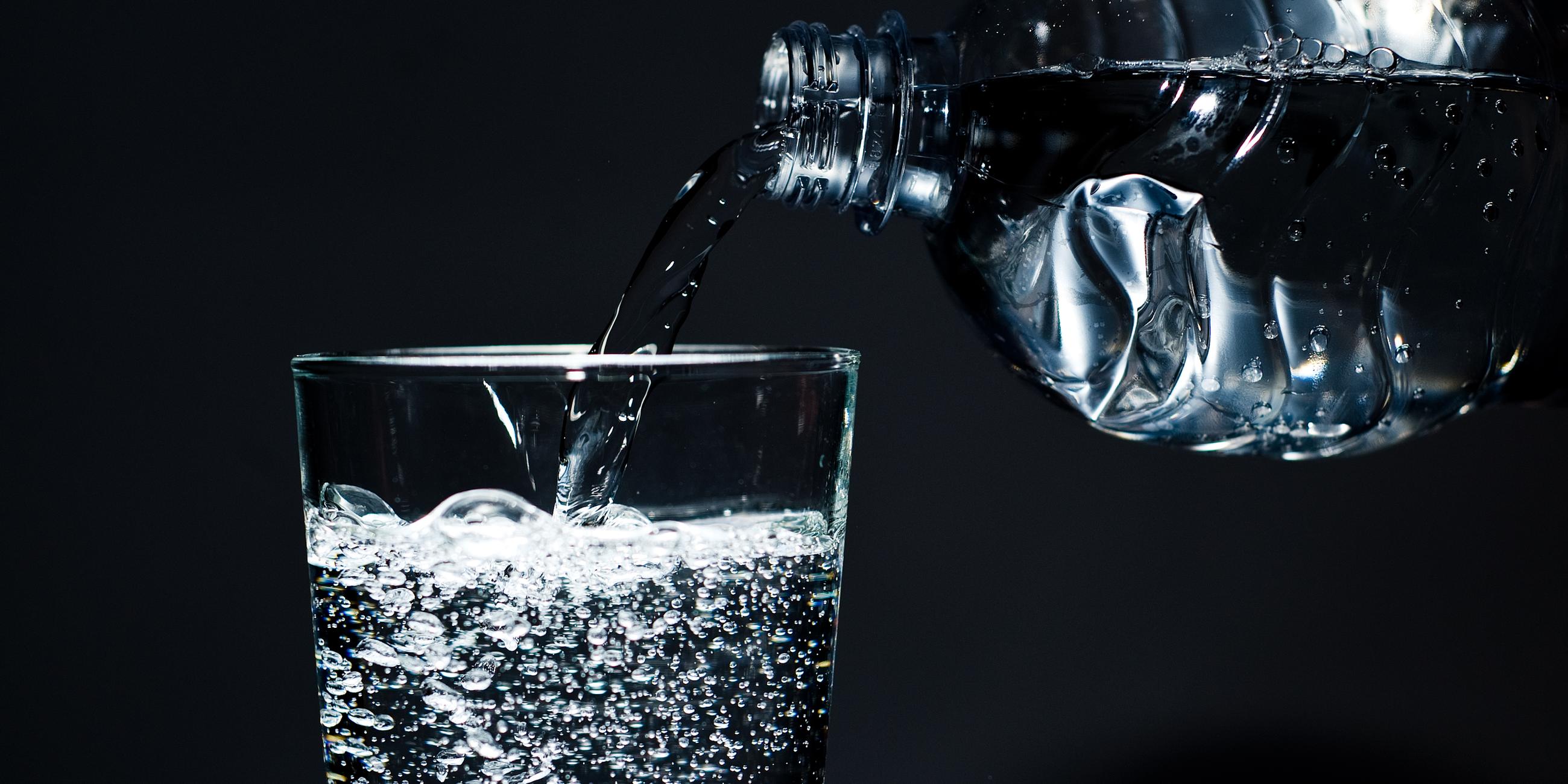 Ein Glas mit kohlensäurehaltigem Mineralwasser wird befüllt.