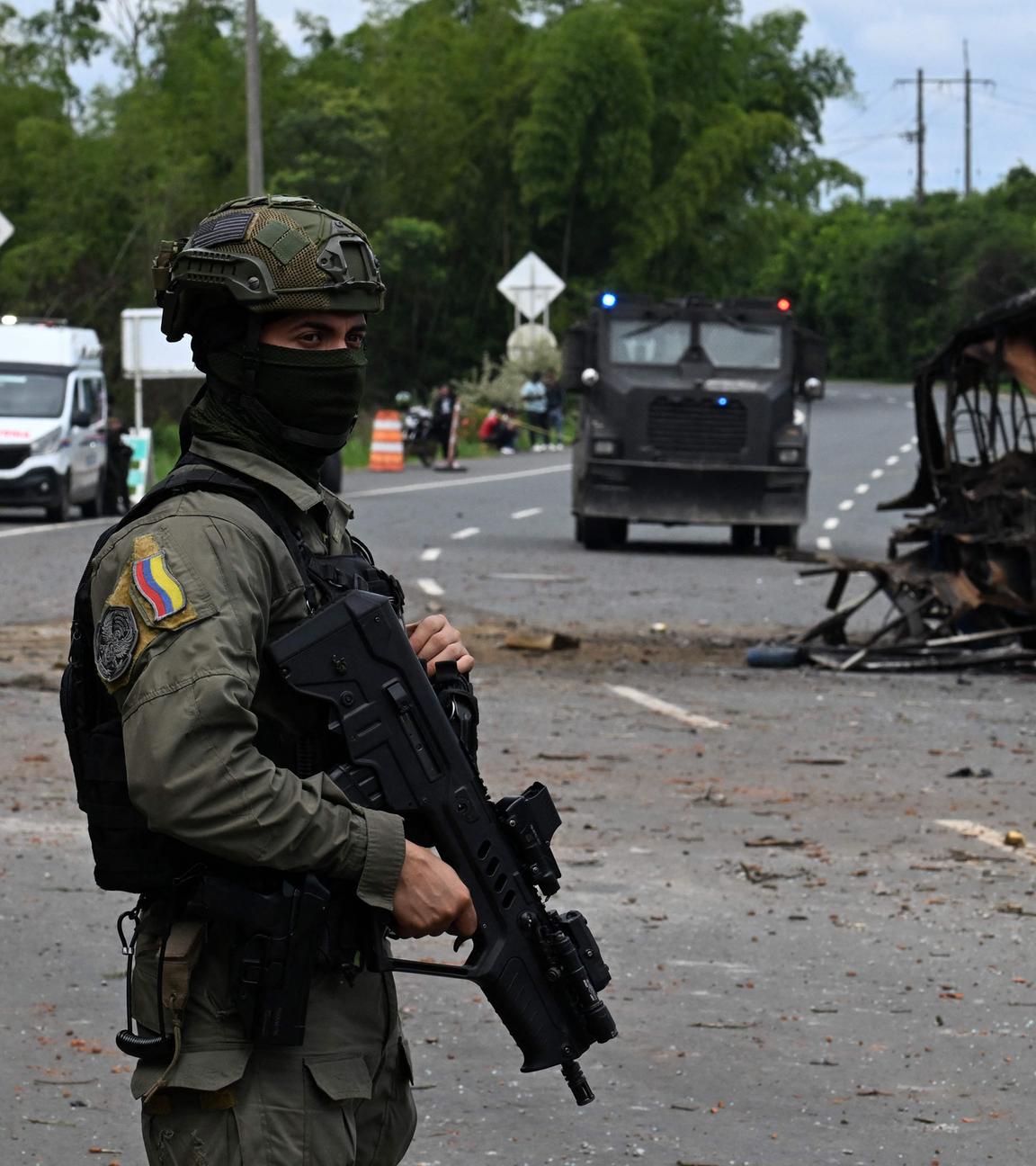 Ein bewaffneter Soldat steht vor einem ausgebrannten Bus auf einer Straße in Villa Rica, Cauca in Kolumbien nach Angriffen der Rebellengruppe FARC.