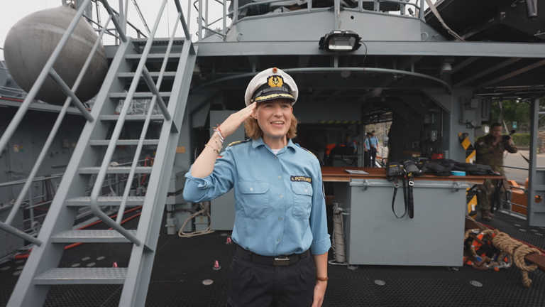 Komandeurin Inka von Puttkamer steht auf dem Marineschiff und salutiert.
