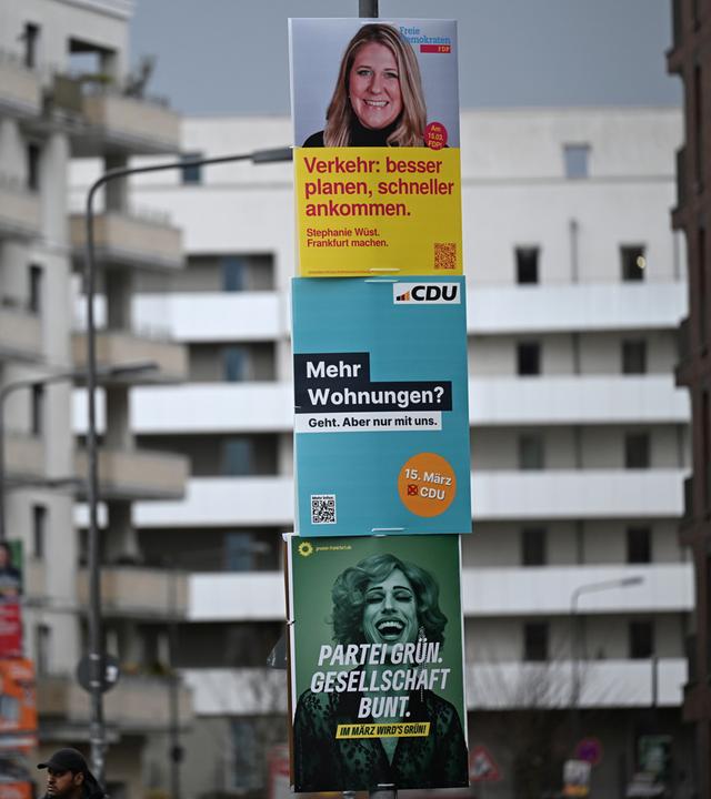 Wahlplakate der FDP, CDU und der Grünen an einer Straßenlaterne in Frankfurt.