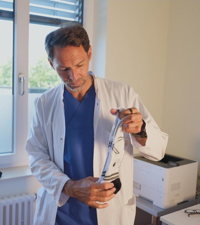 Arzt scchaut sich Kompressionssocken an 