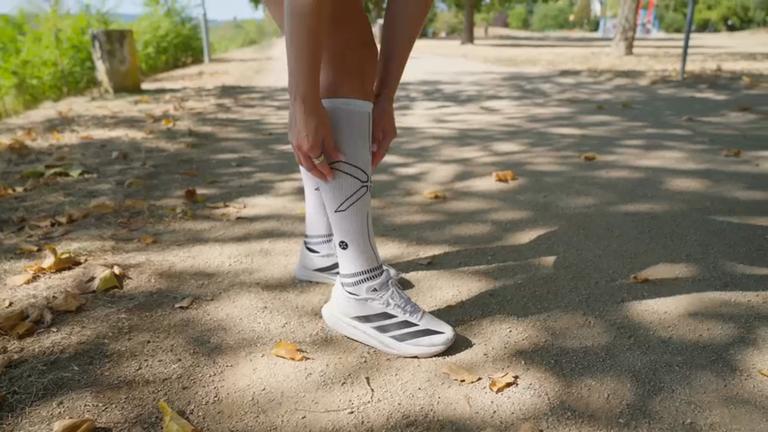 Ausschnitt von denen Beinen einer Joggerin, die Kompressionsstrümpfe trägt und im Freien steht.