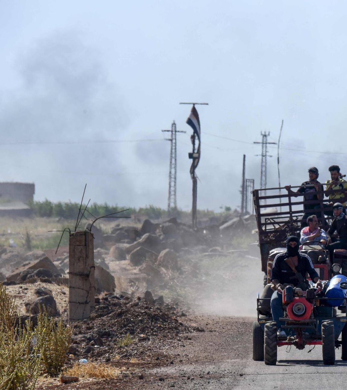Rauch steigt von gemeldeten Kämpfen auf, als Kämpfer von Beduinenstämmen am 18. Juli 2025 auf einer Straße im Dorf al-Mazraa in die überwiegend von Drusen bewohnte Stadt Suweida im Süden Syriens fahren. 