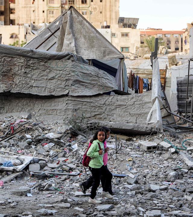 Kinder gehen vor einem Wohngebäude entlang, das am Vortag bei einem israelischen Angriff im Viertel Rimal in Gaza-Stadt getroffen wurde.