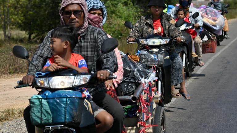 Residents ride their motorbikes along a street after they evacuated following clashes along the Cambodia-Thailand border, in Siem Reap province