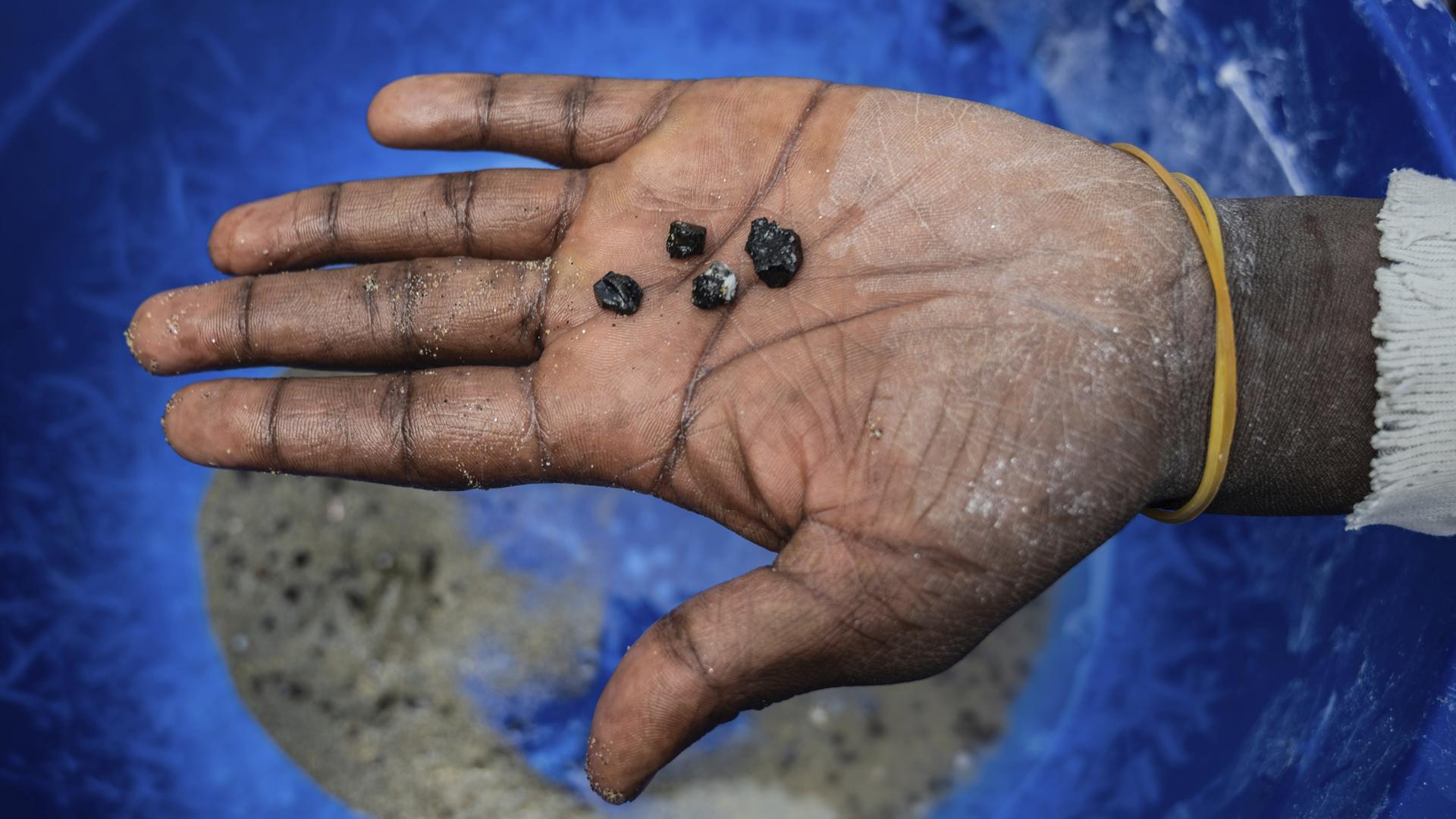 Ein Bergarbeiter hält Stücke von Coltan-Erz in der Hand