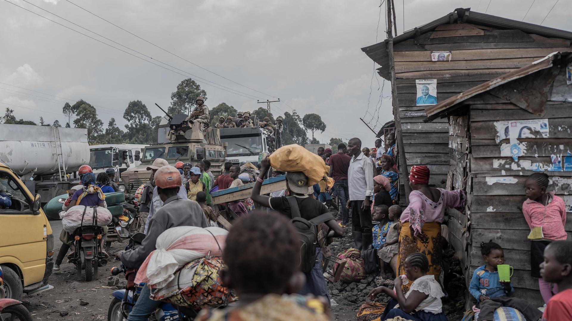 Eine volle Straße in Sake mit wartenden Menschen und Motorradfahrern.