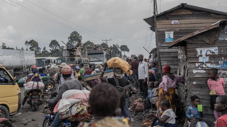 Eine volle Straße in Sake mit wartenden Menschen und Motorradfahrern.