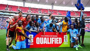 Spieler der DR Kongo feiern hinter einem Schild, auf dem "Qualified" geschrieben steht