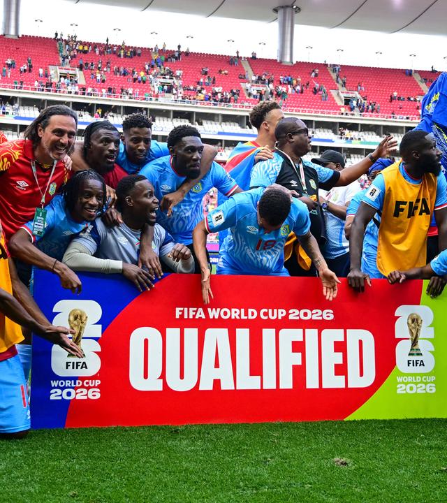 Spieler der DR Kongo feiern hinter einem Schild, auf dem "Qualified" geschrieben steht