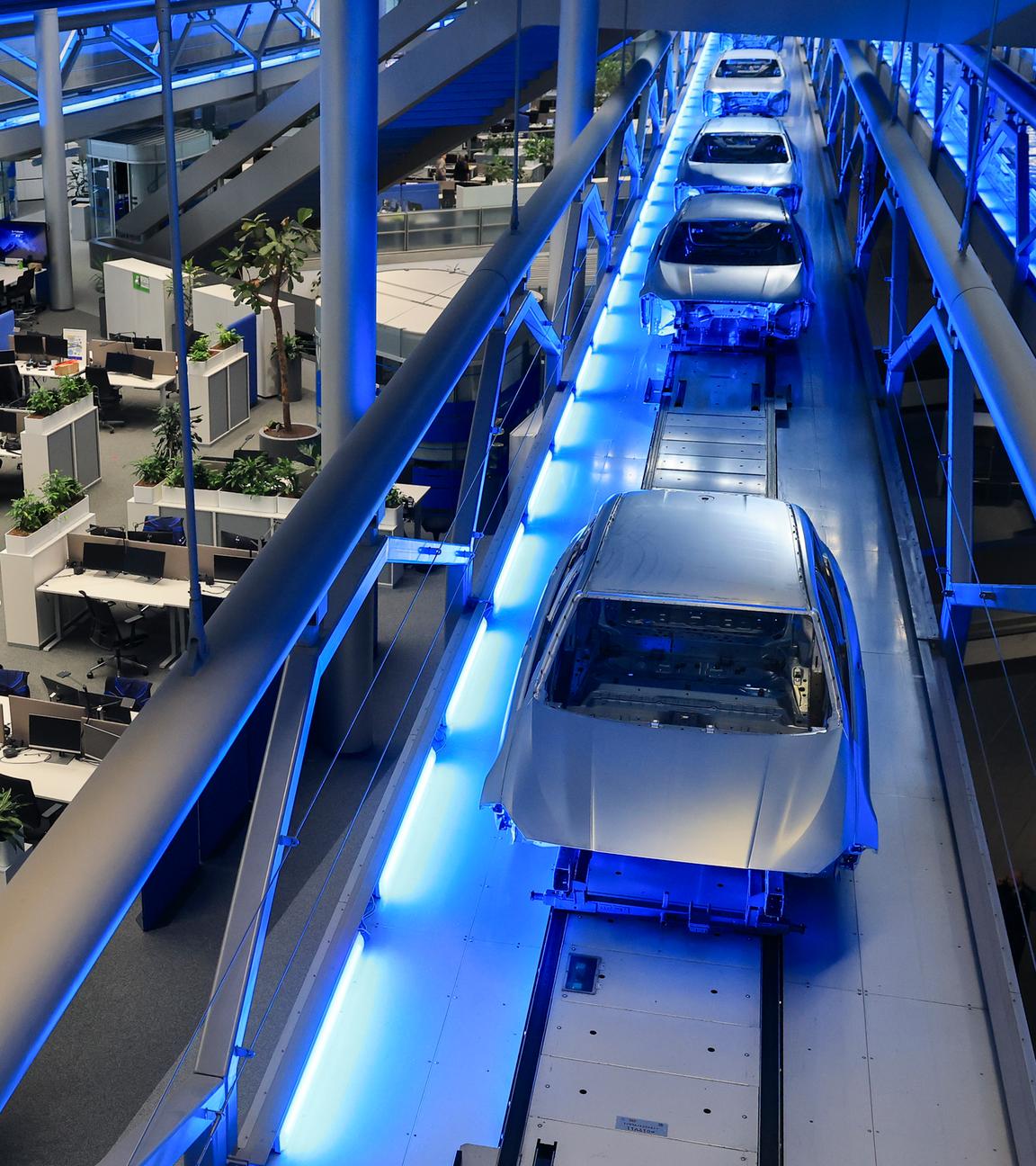 Rohkarossen fahren im Zentralgebäude über die Büroarbeitsplätze zum nächsten Produktionsschritt im BMW Group Werk Leipzig.