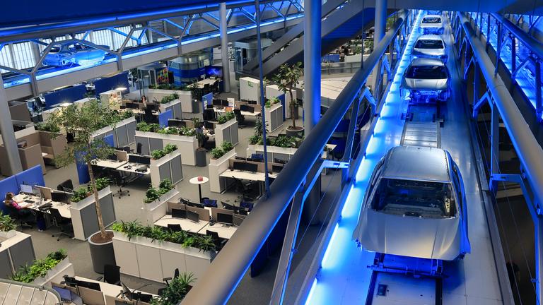 Rohkarossen fahren im Zentralgebäude über die Büroarbeitsplätze zum nächsten Produktionsschritt im BMW Group Werk Leipzig.