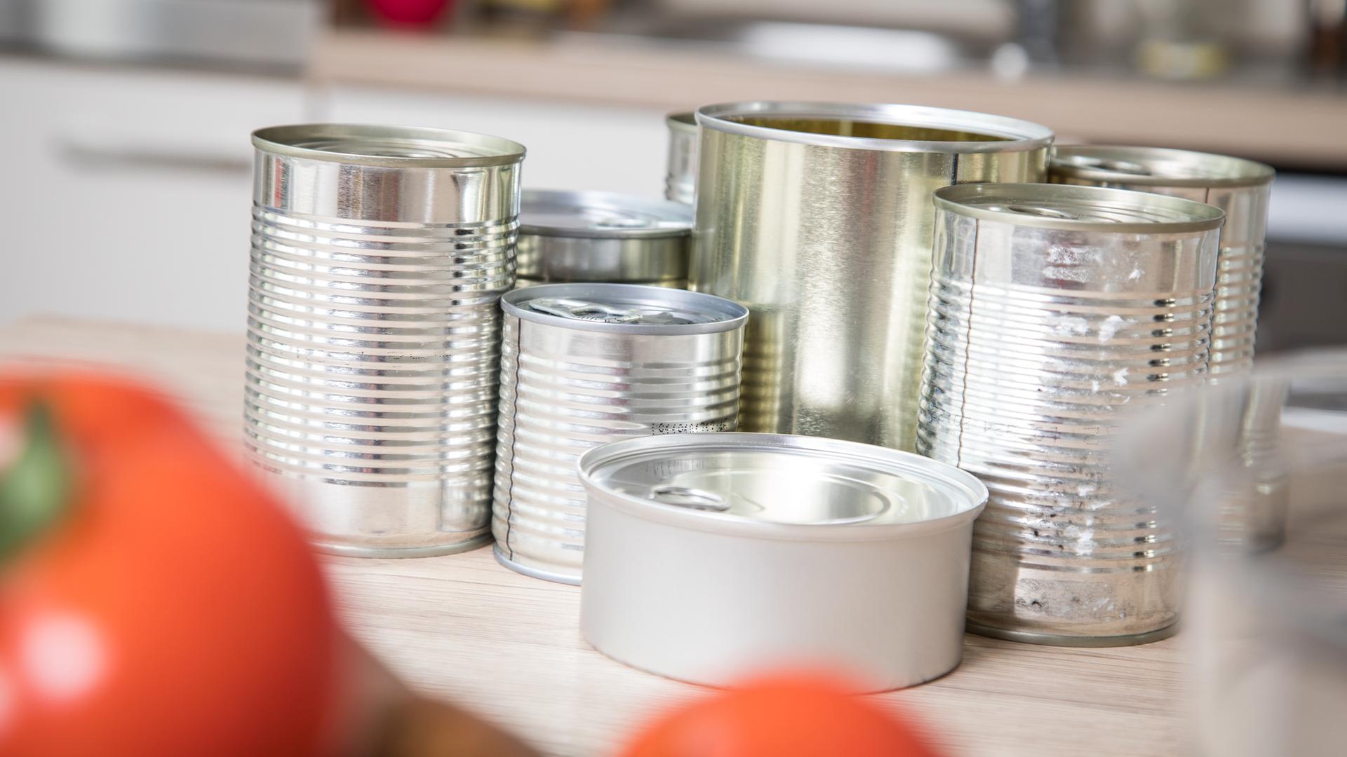 Konservendosen ohne Etikett stehen auf der Arbeitsfläche einer Küche.