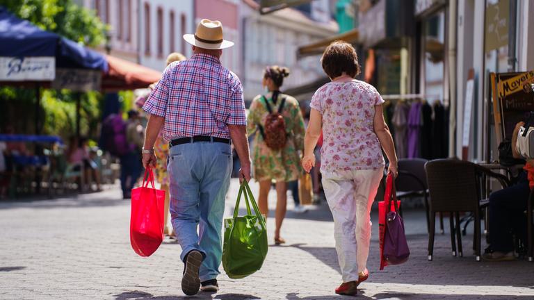 Ein Mann und eine Frau gehen durch die Steingasse in Aschaffenburg. Sie tragen Einkaufstüten und sind von hinten zu sehen.
