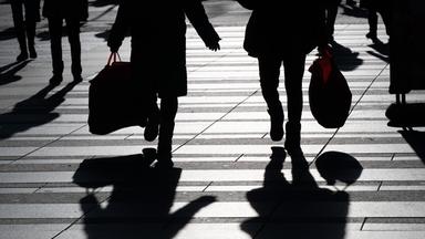 Symbolbild: Passanten mit Einkaufsbeuteln zeichnen sich im Gegenlicht als Silhouette ab. 