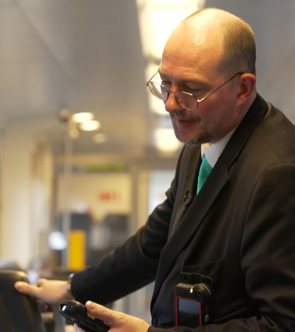 Ein Zugbegleiter kontrolliert Reisende in einer Bahn.