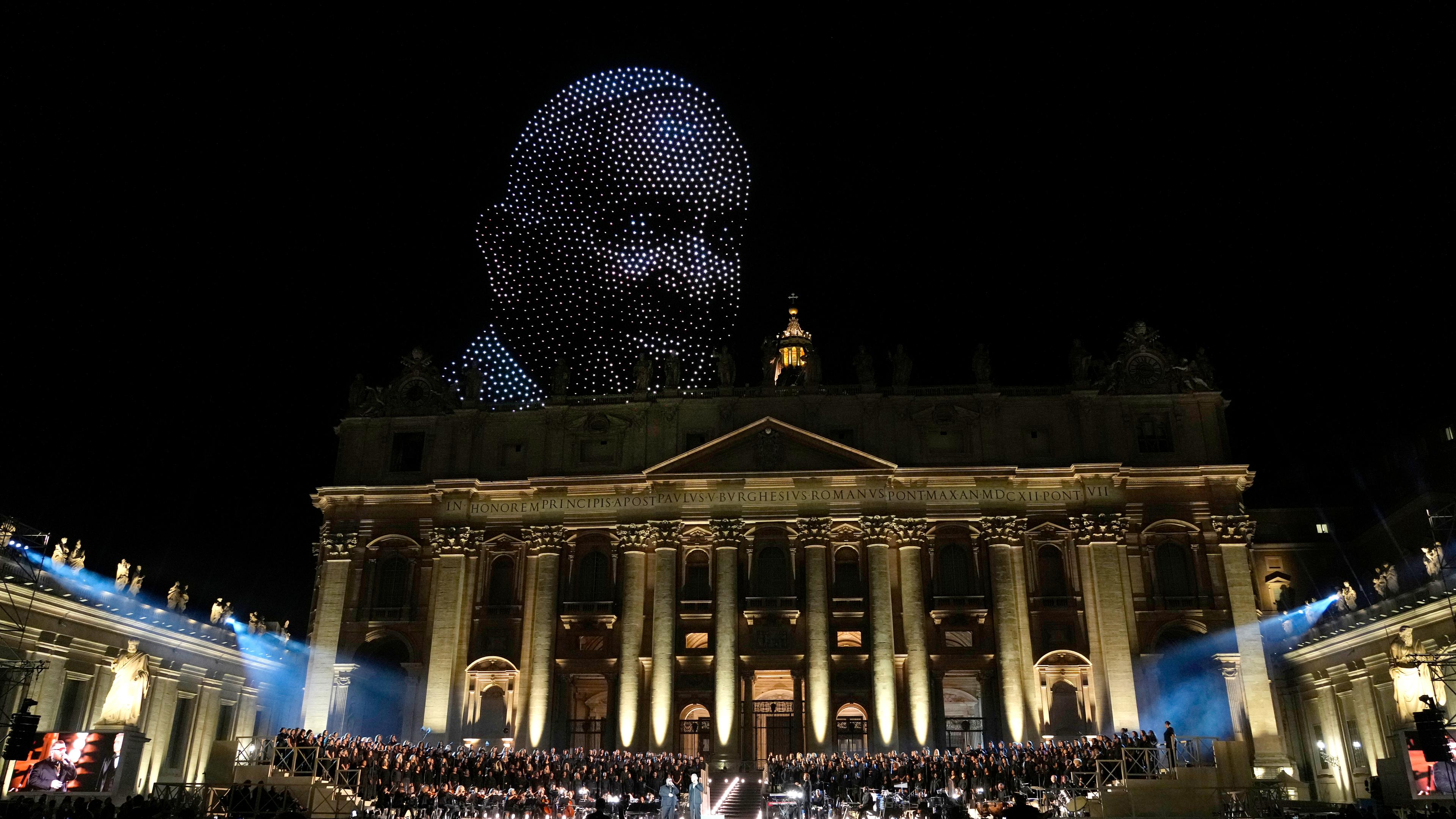 Vatikan, Vatikanstadt: Ein Bild von Papst Franziskus, das von Drohnen über dem Petersdom erstellt ist, erscheint während eines Konzerts auf dem Petersplatz zum Abschluss des Welttreffens über menschliche Brüderlichkeit im Vatikan.