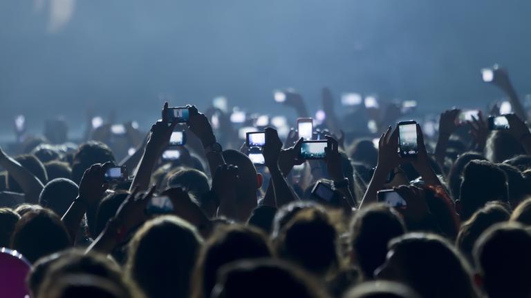 Menschen machen bei einem Konzert Bilder mit dem Smartphone