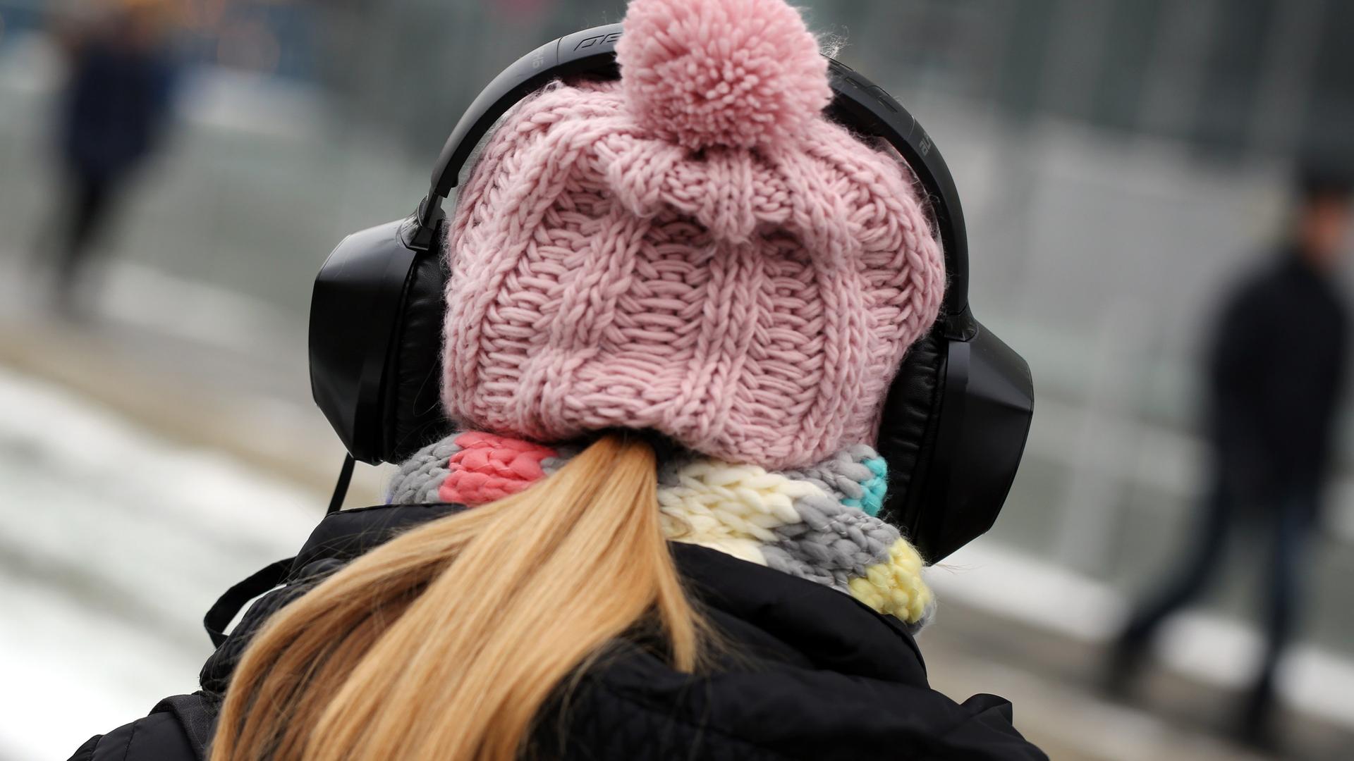 Symbolbild: Junge Frau mit Mütze und Kopfhörern