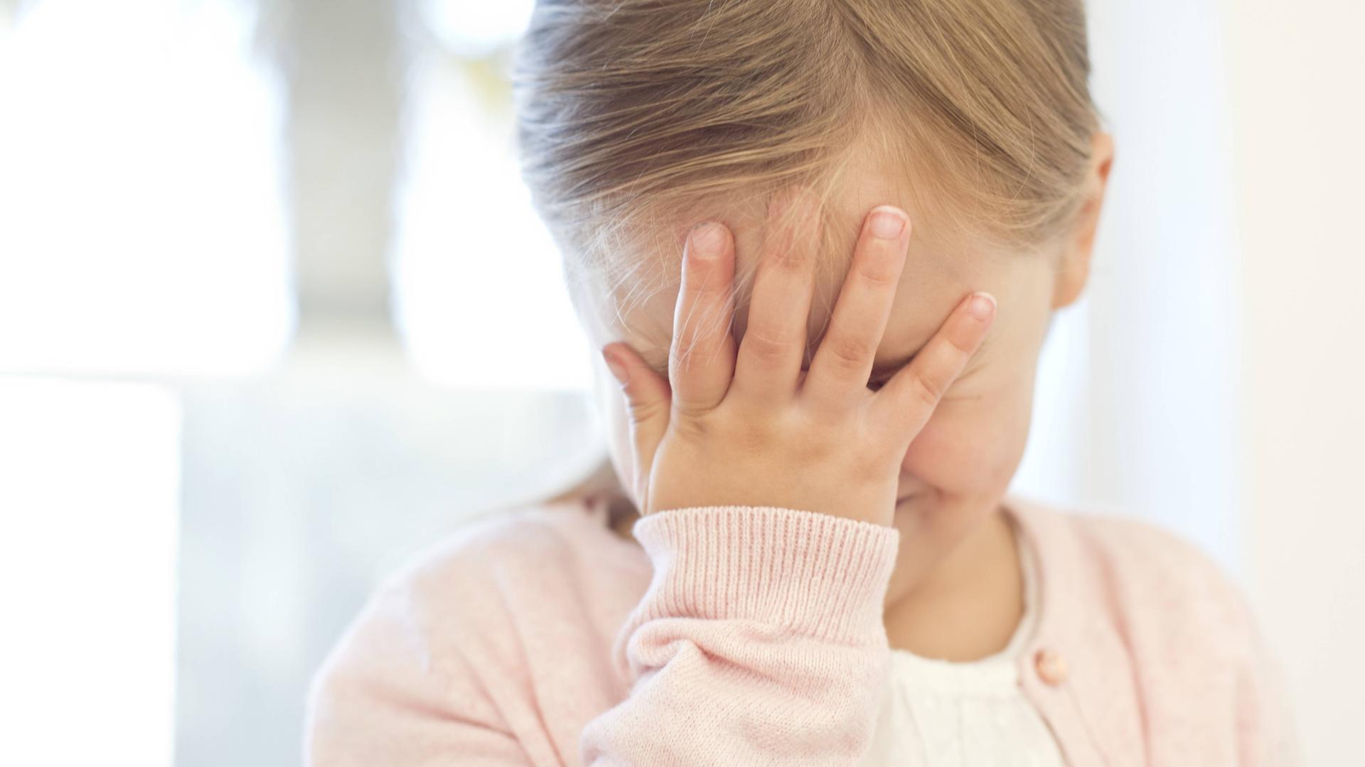 Kind fasst sich an die Stirn.