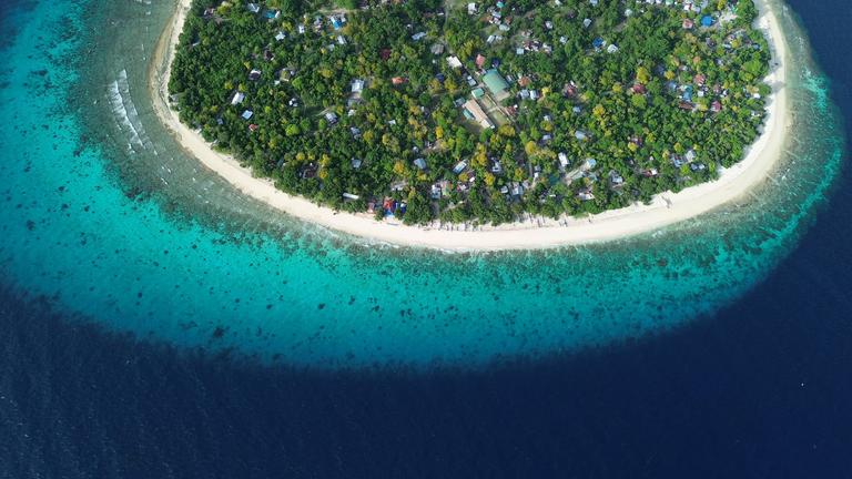 Tropische Insel mit türkisfarbenem Wasser und Korallenriff.