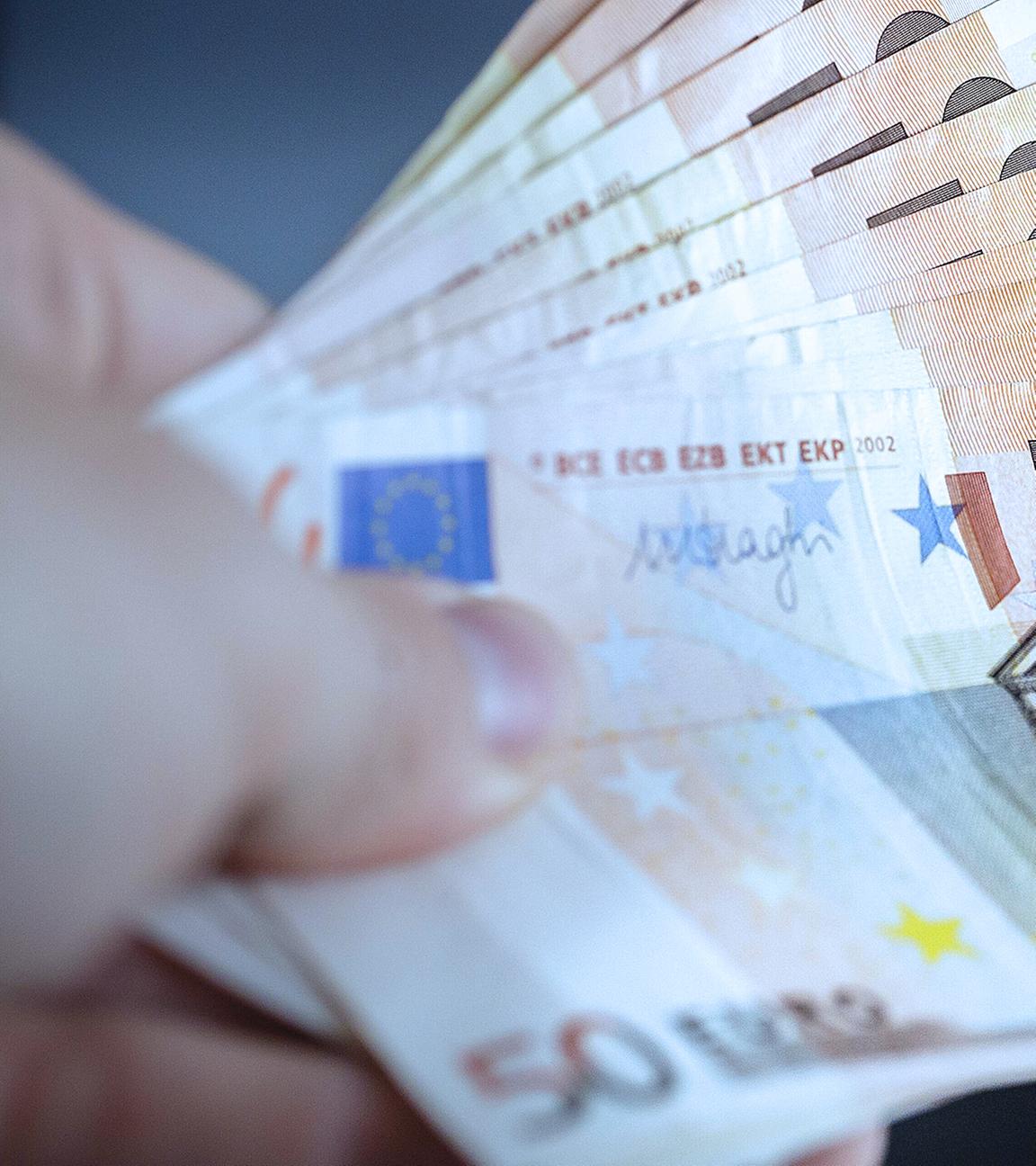 Archiv: Eine Person übergibt Geldscheine an eine andere Person. Berlin, Deutschland. 02.08.2016