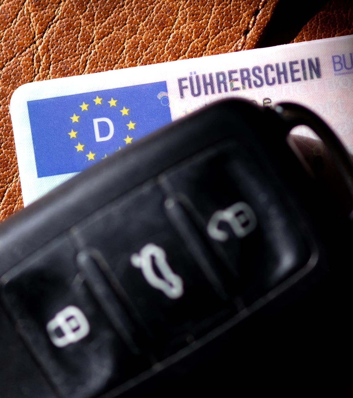 03.03.2025, Bayern, München: Ein Führerschein und ein Autoschlüssel liegen auf einem Portemonnaie. 