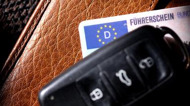 03.03.2025, Bayern, München: Ein Führerschein und ein Autoschlüssel liegen auf einem Portemonnaie. 