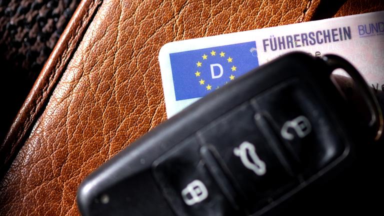 03.03.2025, Bayern, München: Ein Führerschein und ein Autoschlüssel liegen auf einem Portemonnaie. 