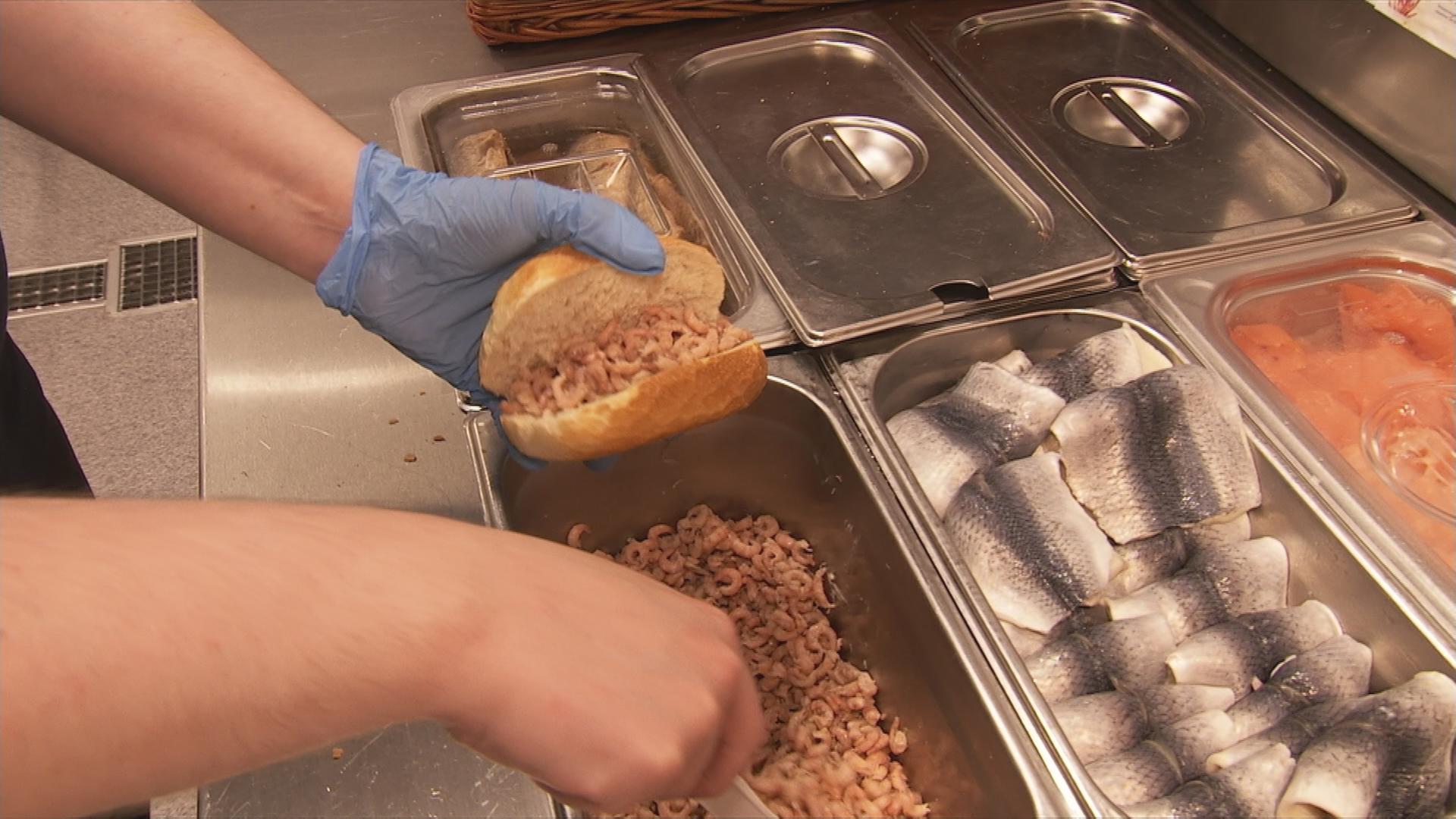 Verkäuferin belegt Krabbenbrötchen