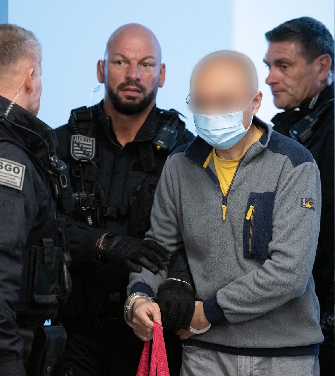 05.08.2025, Sachsen, Dresden: Der Hauptangeklagte Jian G. (2.v.r.) wird vor Prozessbeginn in den Gerichtssaal geführt.