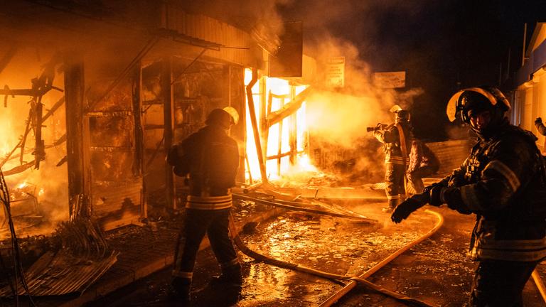 Feuerwehrleute arbeiten daran, die Flammen einzudämmen, die aus dem zentralen Markt in Kramatorsk aufsteigen, nachdem ein russischer Drohnenangriff das Gebiet in Brand gesetzt hat. 