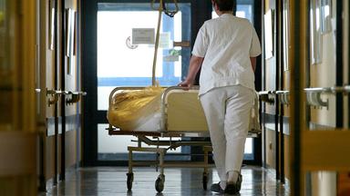 Eine Krankenschwester schiebt eine Patientin im Bett, aufgenommen am 03.05.2002 in Berlin