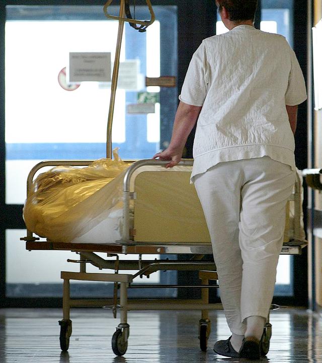 Eine Krankenschwester schiebt eine Patientin im Bett, aufgenommen am 03.05.2002 in Berlin