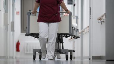 Pflegekraft zieht ein Krankenbett durch den Gang eines Krankenhauses