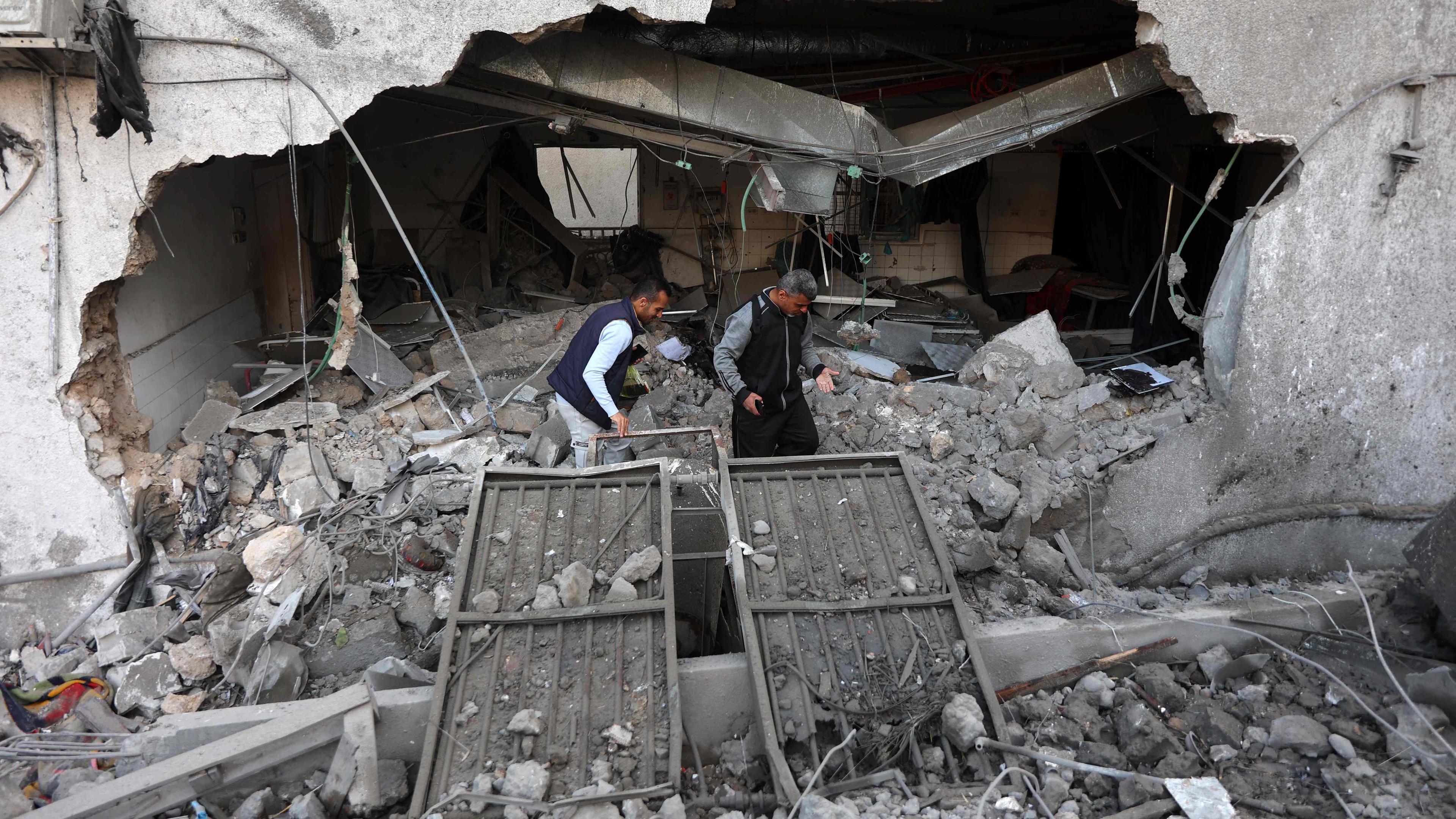 Zwei Männern stehen in den Trümmern des Al-Ahli-Krankenhauses in Gaza-Stadt, nachdem dieses von einem israelischen Angriff zerstört wurde.