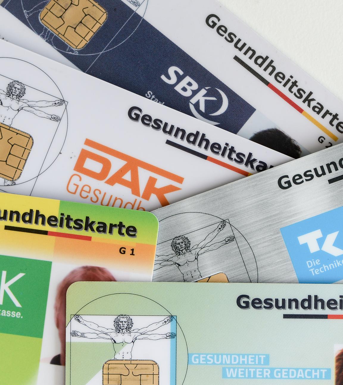  Gesundheitskarten verschiedener Krankenkassen liegen auf einem Tisch.
