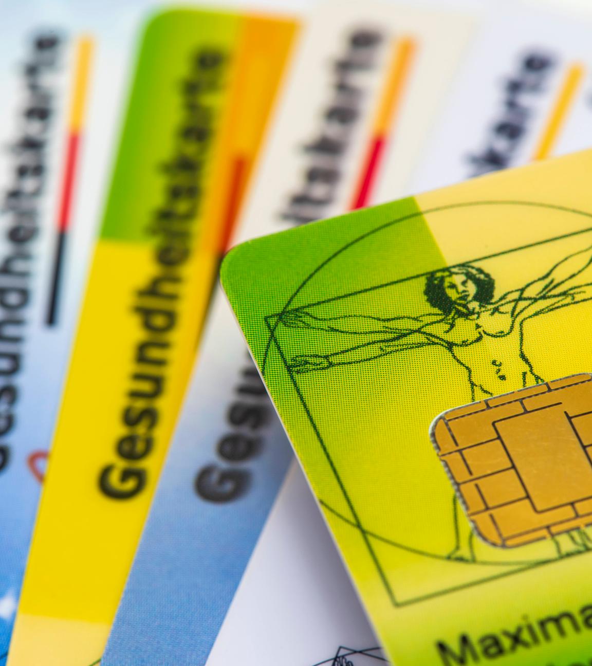 Viele Gesundkeitskarten von verschiedenen Krankenkassen liegen zusammen.