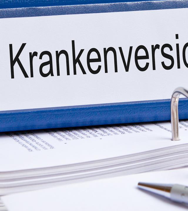 Ein Ordner mit der Aufschrift" Krankenkasse" liegt auf einem Tisch. 