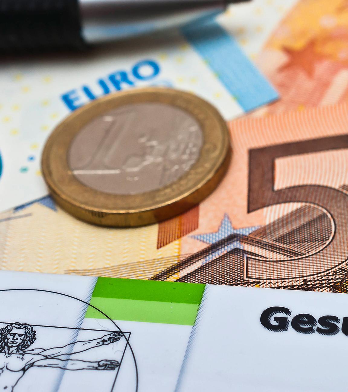 Krankenversicherungskarten, Geld und Taschenrechner liegen auf einem Tisch.