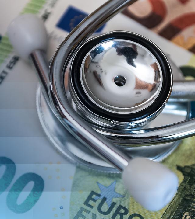 Ein Stethoskop liegt auf Geldscheinen.