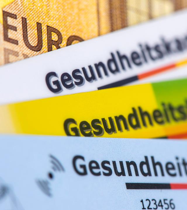 Verschiedene Krankenversicherungskarten von Krankenkassen werden gemeinsam als symbolisches Bild des Gesundheitssystems auf der Grundlage der gesetzlichen Krankenversicherung dargestellt. 