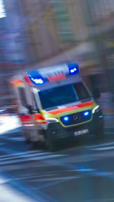 Ein Rettungsfahrzeug ist mit Blaulicht auf einer Straße unterwegs.