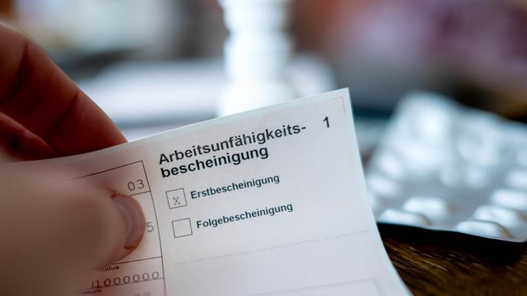 Eine Person hält eine ausgefüllte Arbeitsunfähigkeitsbescheinigung in der Hand