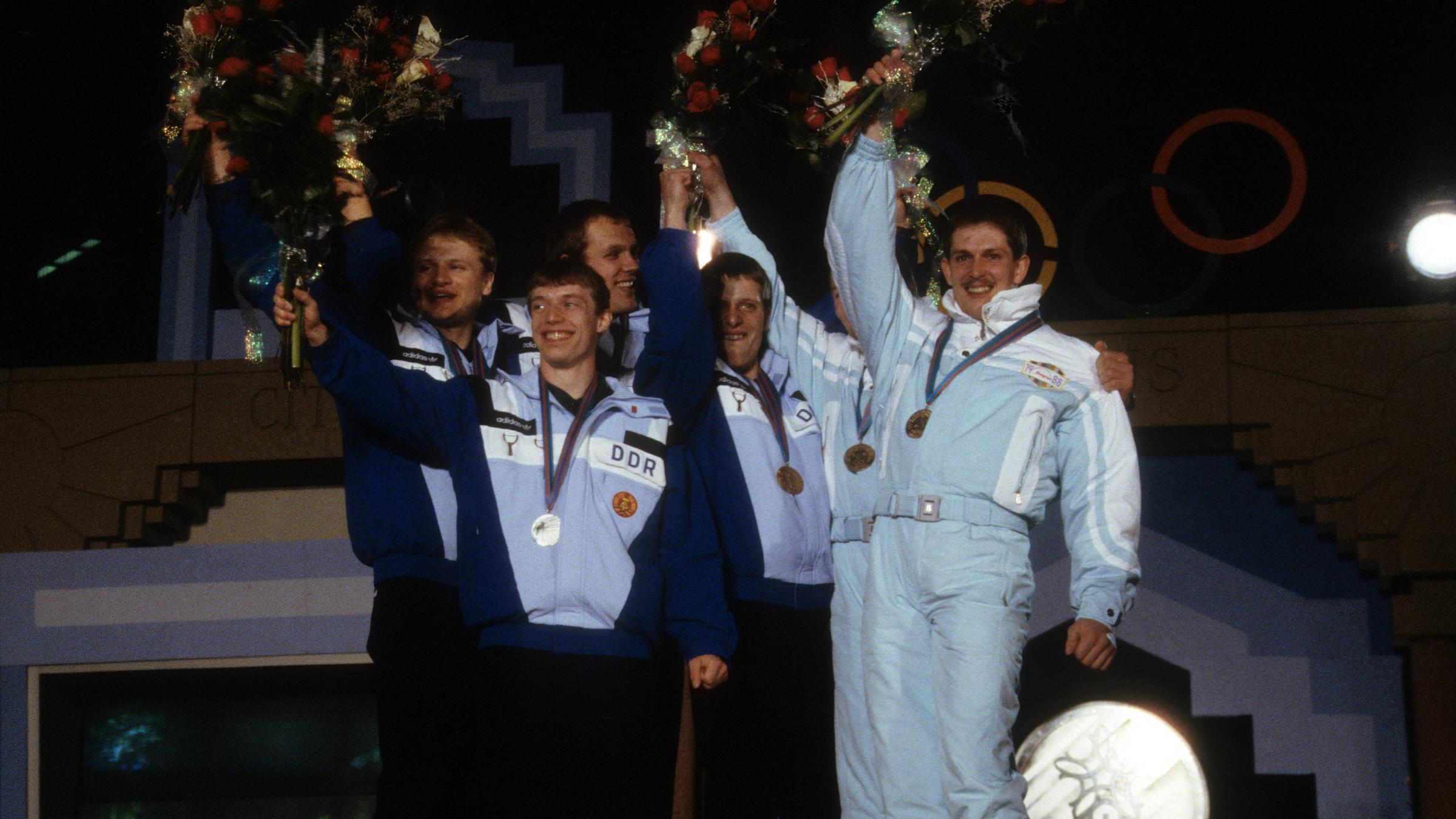 Die Rennrodler Stefan Krauße, Jan Behrendt, Jörg Hoffmann, Jochen Pietzsch, Thomas Schwab und Wolfgang Staudinger bei der Siegerehrung der Olympischen Winterspiele 2026 in Calgary