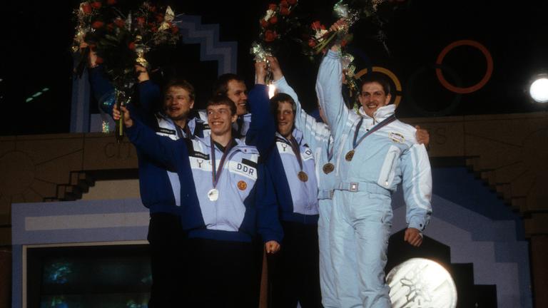 Die Rennrodler Stefan Krauße, Jan Behrendt, Jörg Hoffmann, Jochen Pietzsch, Thomas Schwab und Wolfgang Staudinger bei der Siegerehrung der Olympischen Winterspiele 2026 in Calgary