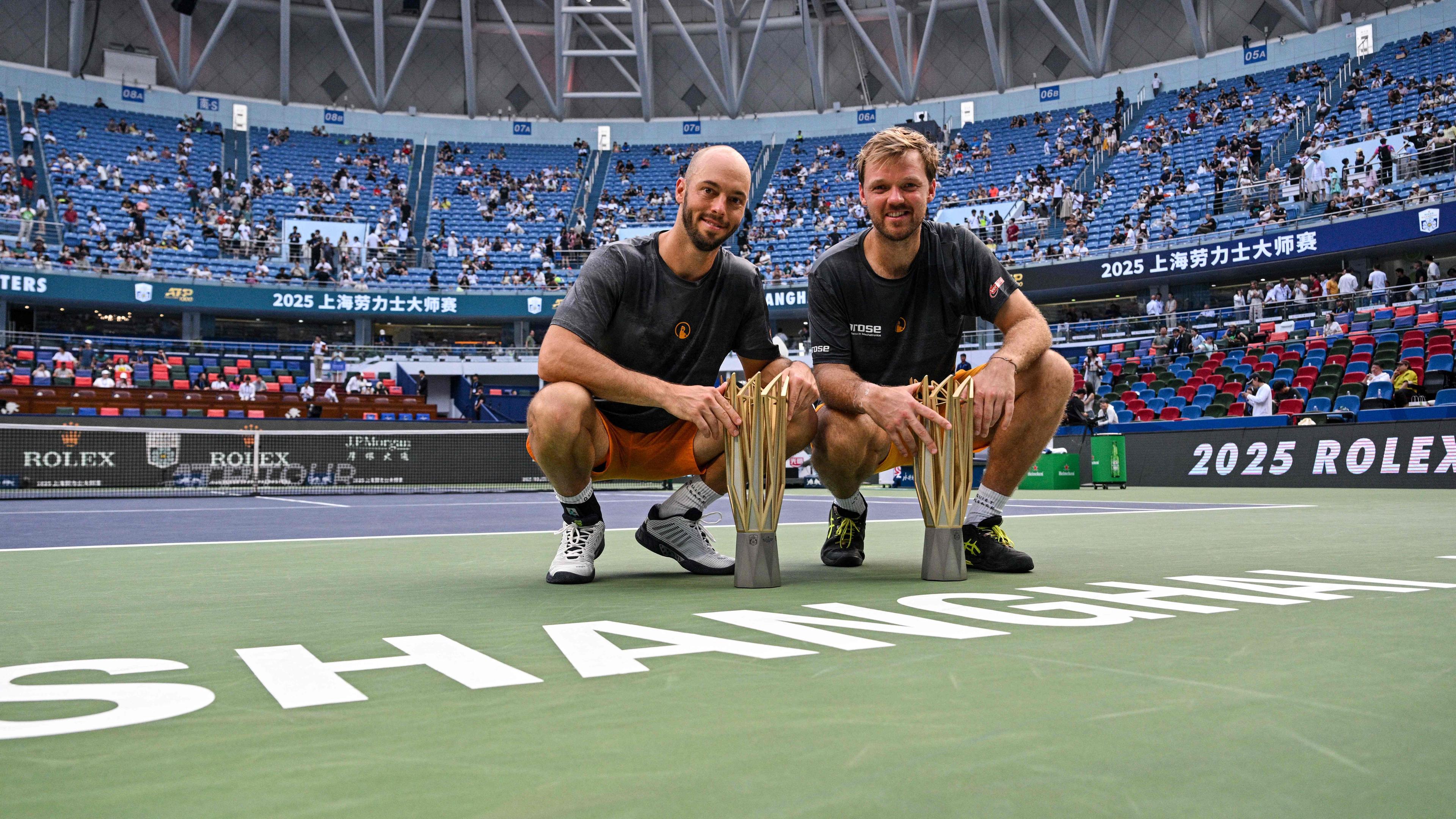 Tim Pütz (links) und sein Doppelpartner Kevin Krawietz sind auf dem Court in Shanghai in die Hocke gegangen. Vor ihnen ihr Siegerpokal.